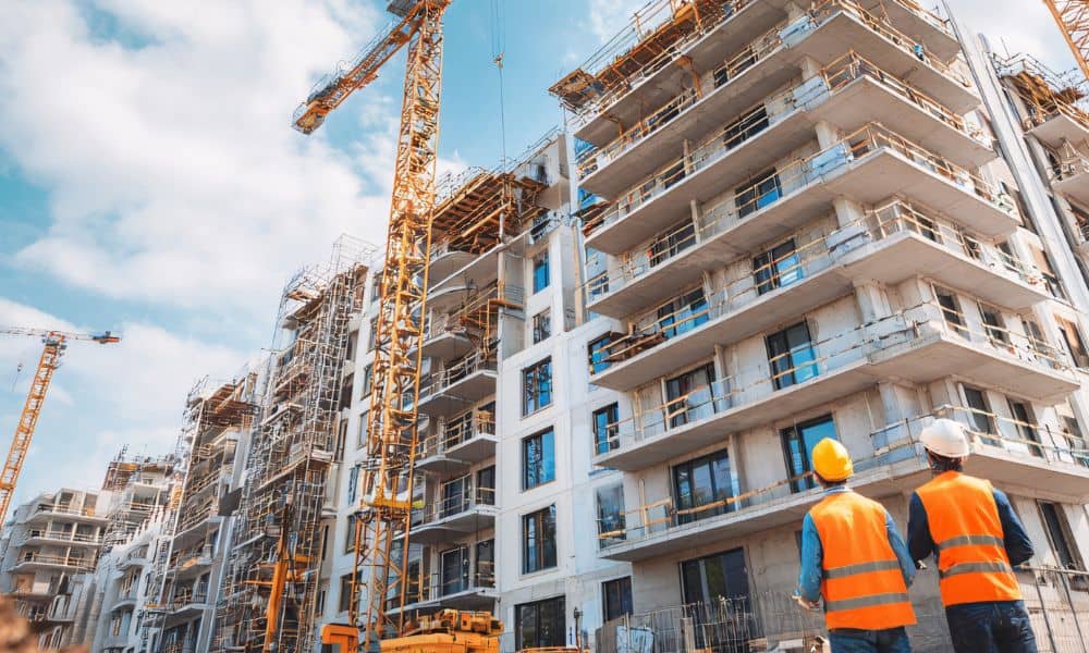 Two construction professionals inspecting a multi-story urban building site with cranes, symbolizing how an ALTA survey supports compliance under new state housing laws