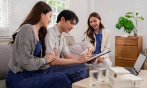 Homebuyers signing paperwork with an agent during a loan closing survey review