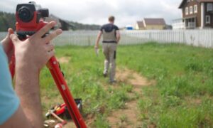 Land surveyor measuring a residential property for an elevation certificate and flood insurance review