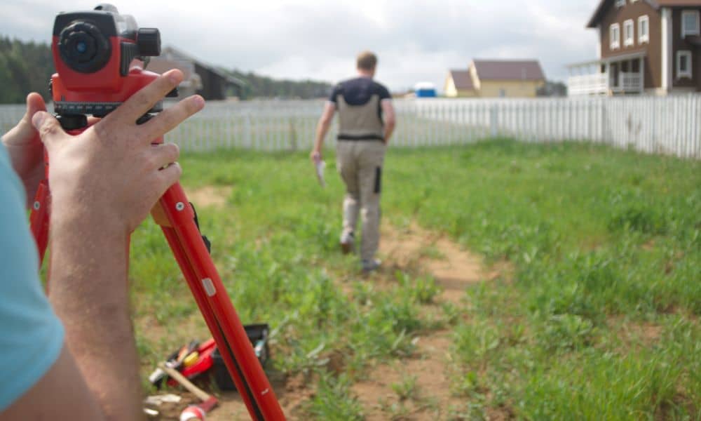Land surveyor measuring a residential property for an elevation certificate and flood insurance review