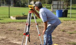 Licensed land surveyor measuring property boundaries using professional surveying equipment