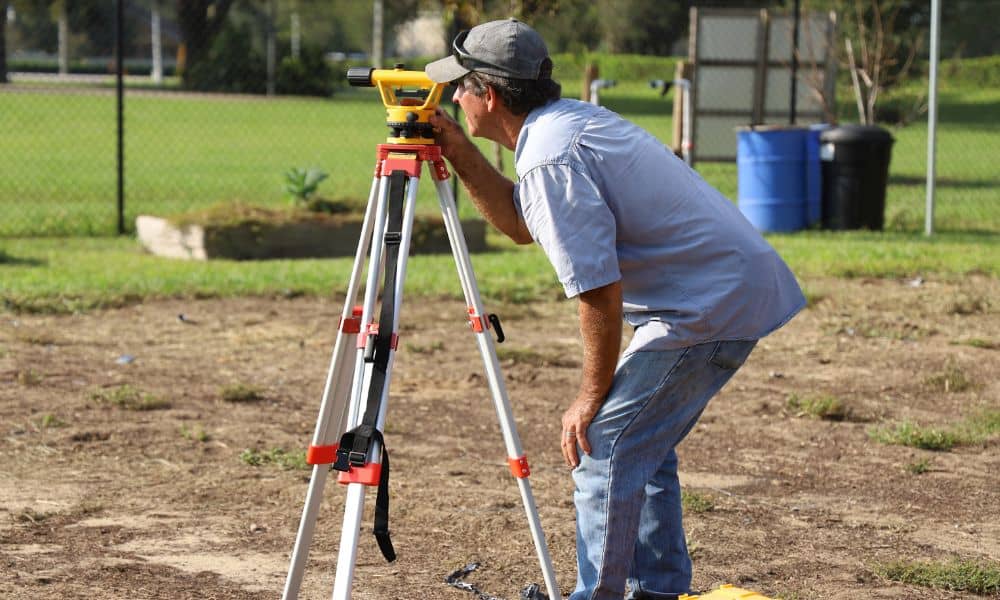 Licensed land surveyor measuring property boundaries using professional surveying equipment