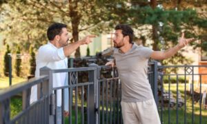 Two neighbors arguing over a boundary line survey issue near a fence