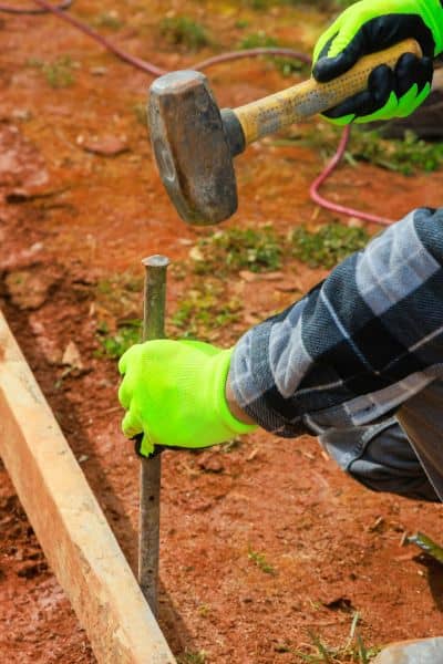 Licensed land surveyor placing a boundary marker stake to confirm property lines