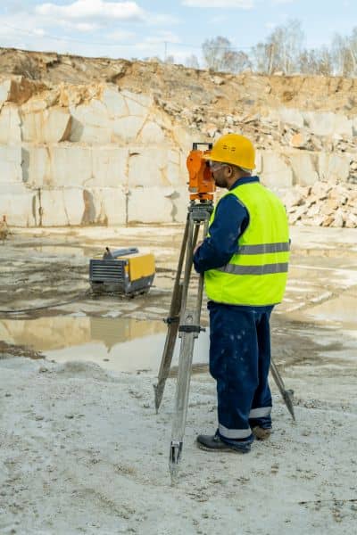 Surveyor using a total station to monitor ground movement after a landslide