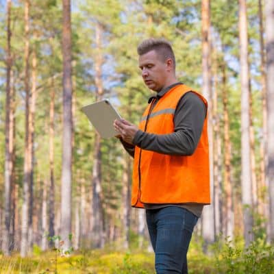 Licensed land surveyor reviewing digital property maps and site data on a tablet during survey planning