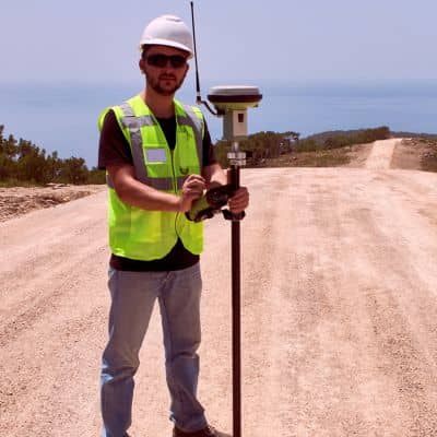 Surveyor using GNSS equipment to improve topographic survey accuracy and measure elevation changes on sloped terrain