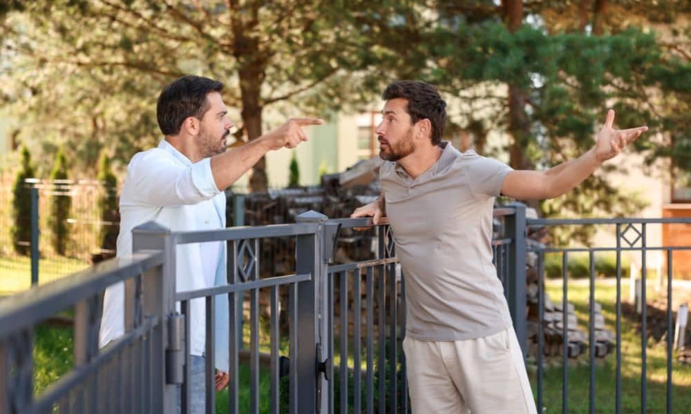 Two neighbors arguing over a boundary line survey issue near a fence