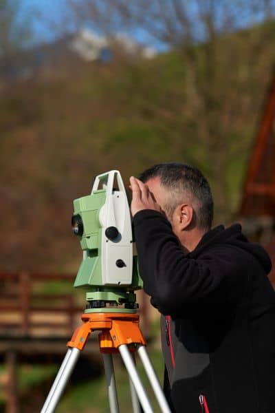 Licensed land surveyor using equipment to perform a boundary line survey